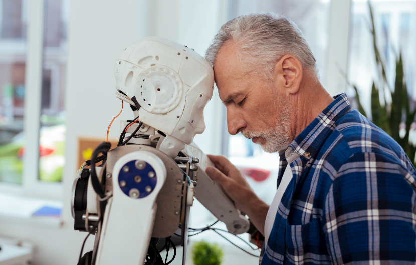 An elderly man is leaning towards his personal robot