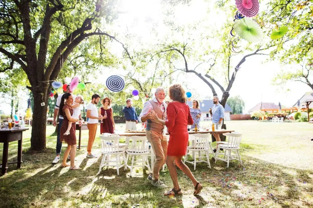 A senior couple dancing on a garden party outside