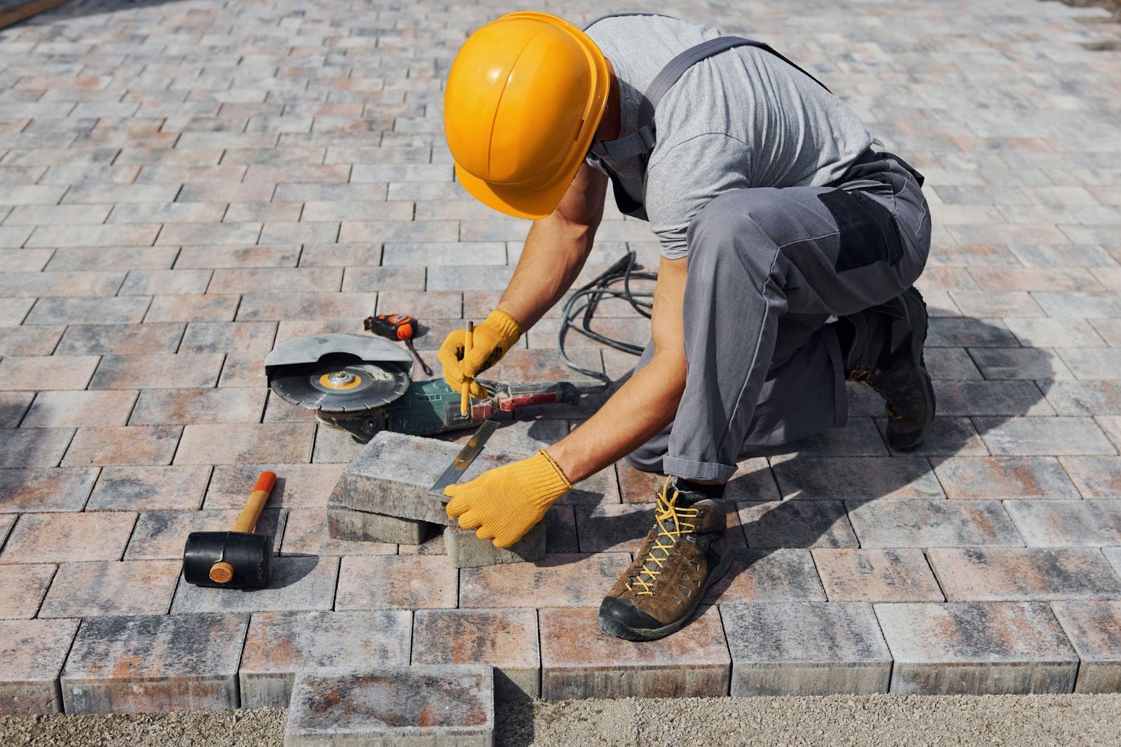 Male worker in yellow uniform laying pavers