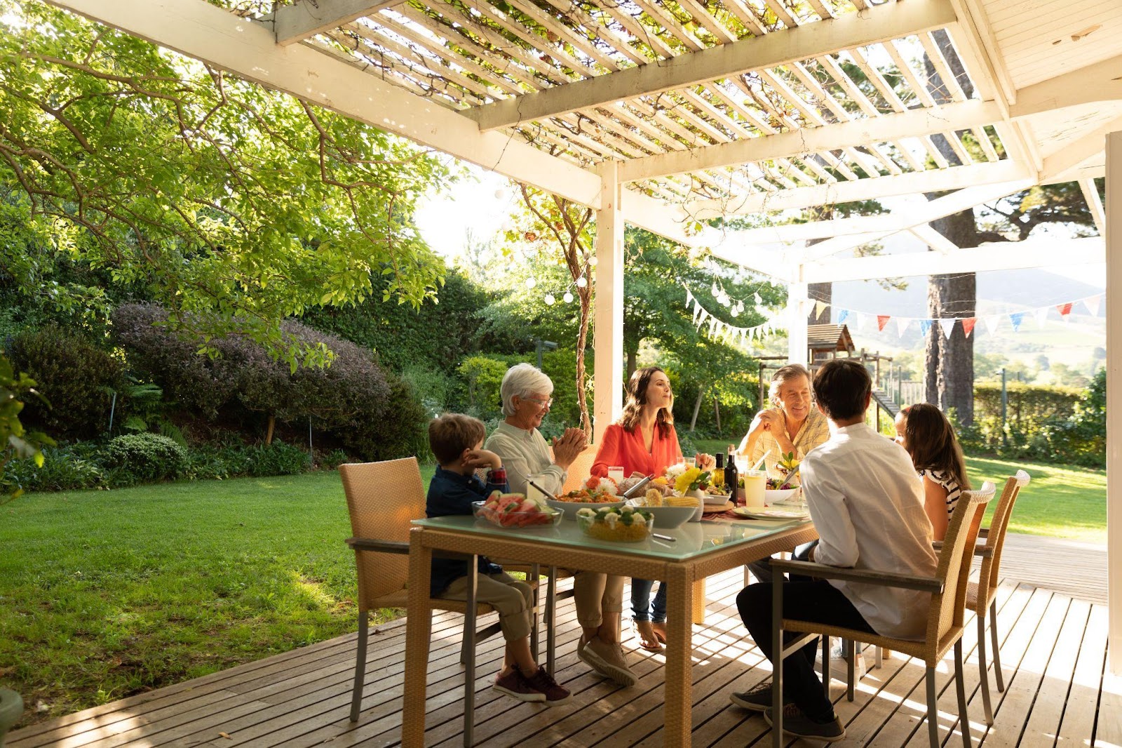 Family eating together outdoor on a wooden patio.